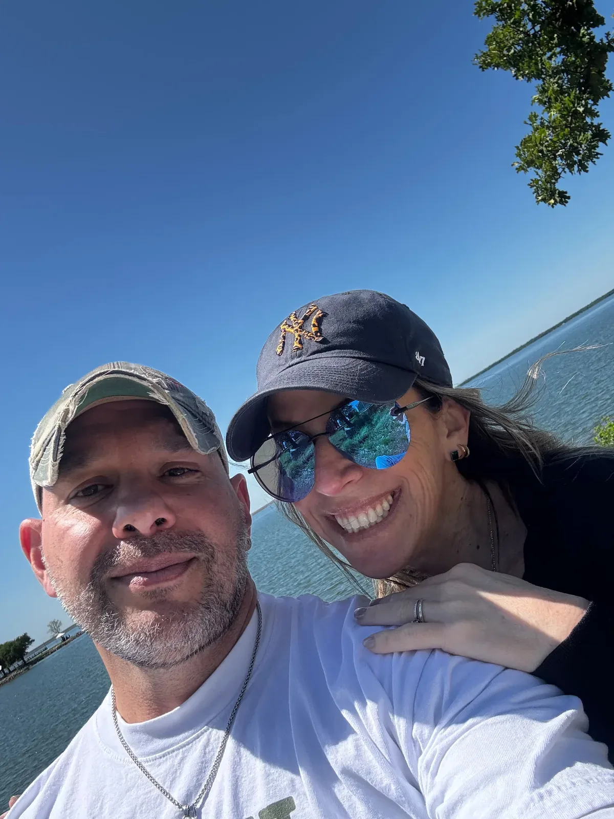 Wilson and his wife smiling by the water on a sunny day