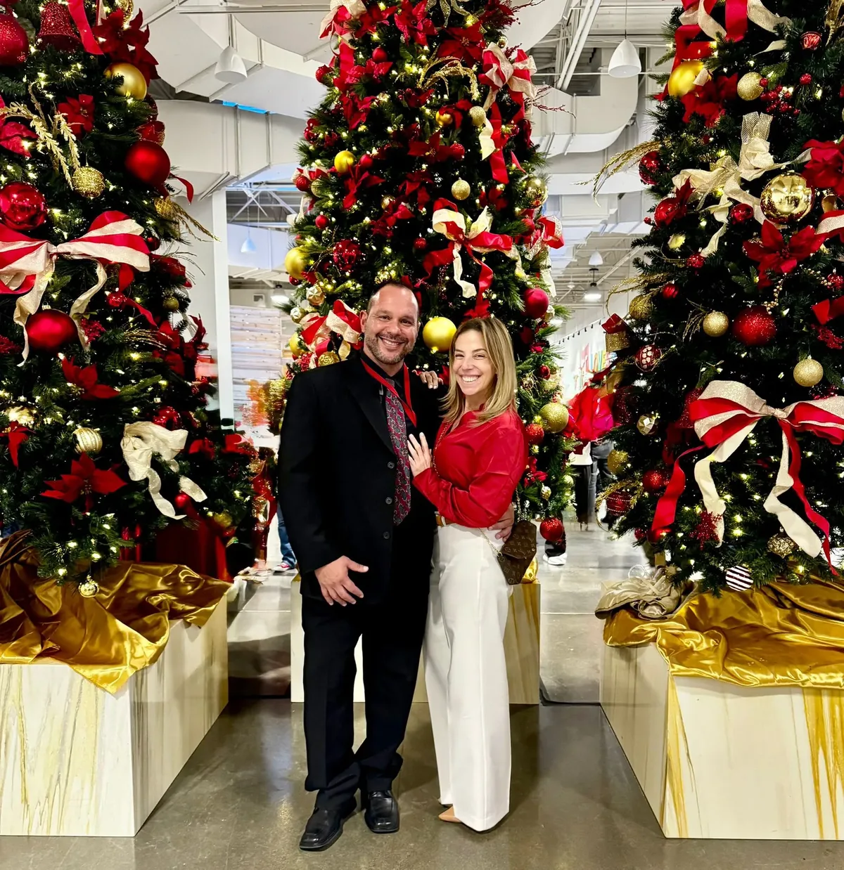 Wilson and his wife in front of decorated Christmas trees