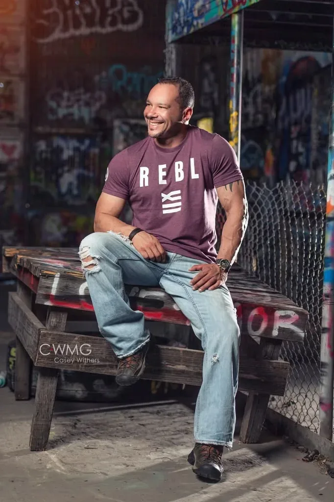 Wilson Machado sitting for a studio portrait against a graffiti wall