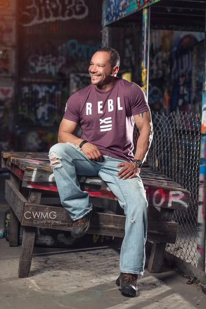 Wilson Machado sitting for a studio portrait against a graffiti wall